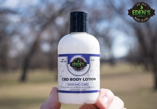 Hand holding a bottle of CBD body lotion from eden's herbals