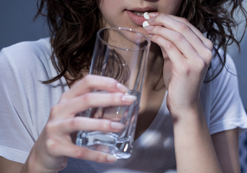 Woman taking a CBD pill with glass of water