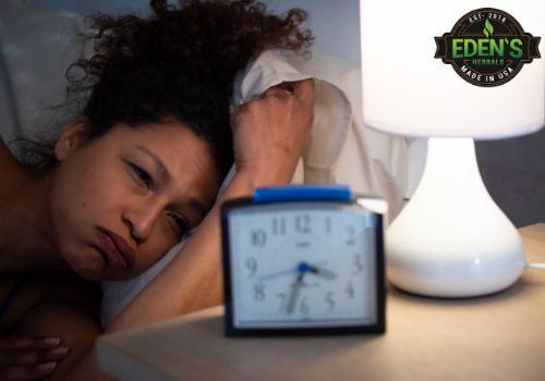 woman laying in bed staring at clock because she can't sleep