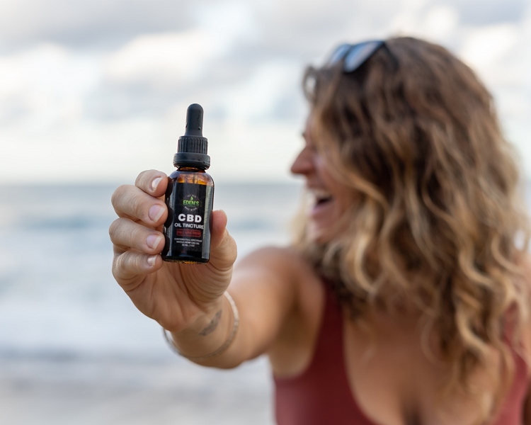 Woman laughing and holding up full spectrum CBD oil tincture