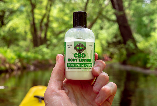 Hand holding up cbd lotion from eden's herbals