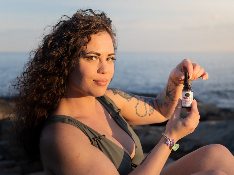 Woman holding up tincture of pain relieving CBD oil