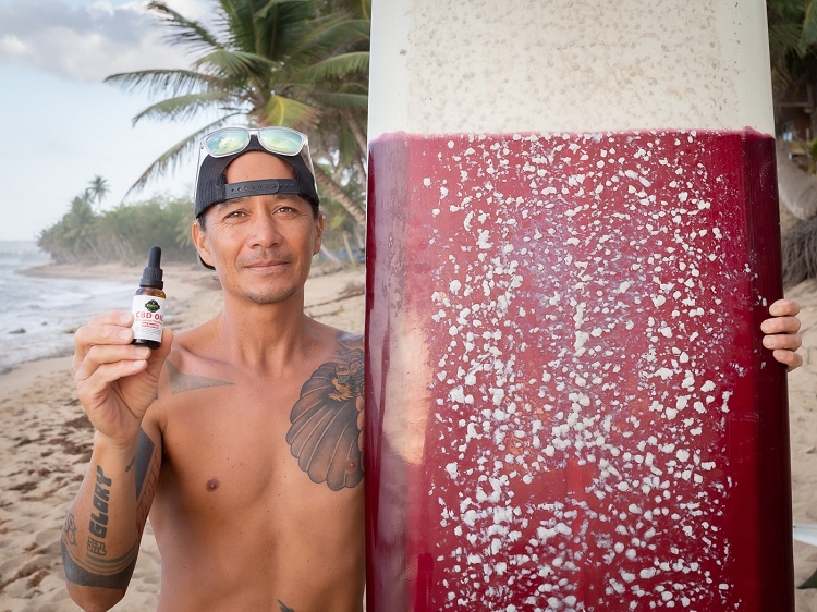 Man using CBD oil to suppress nausea from sea sickness while surfing