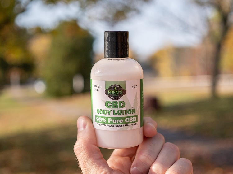 Hand holding up CBD body lotion from Eden's Herbals