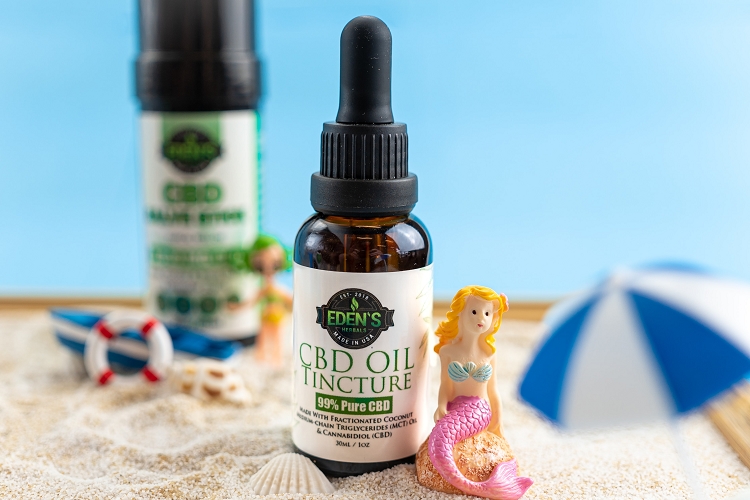 Edens Herbals CBD Oil Tincture and CBD Salve Stick in miniature beach themed scene