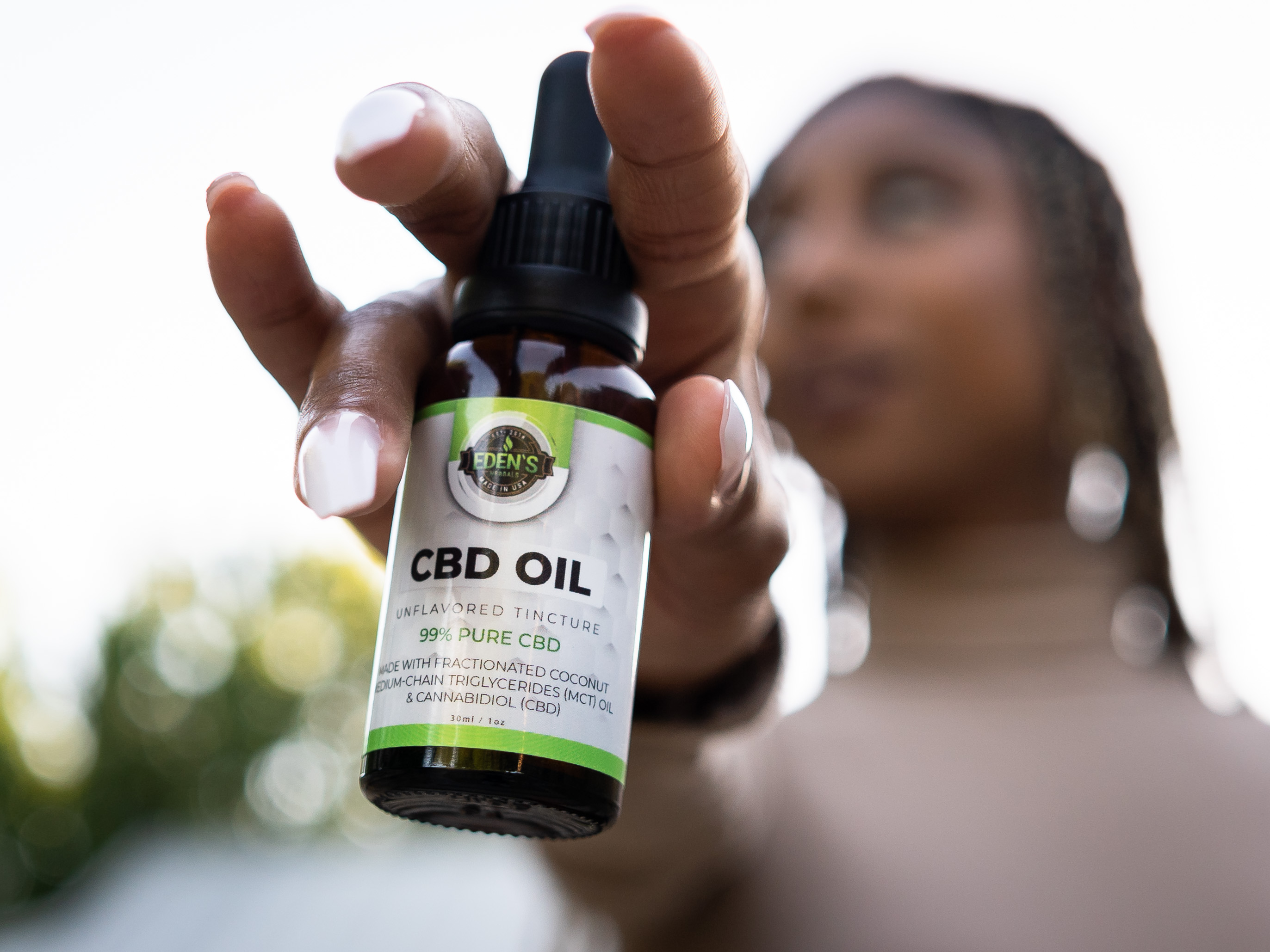 Closeup of cbd oil tincture held up by woman