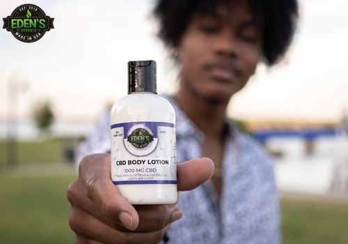 man holding eden's herbals cbd lotion close to camera 
