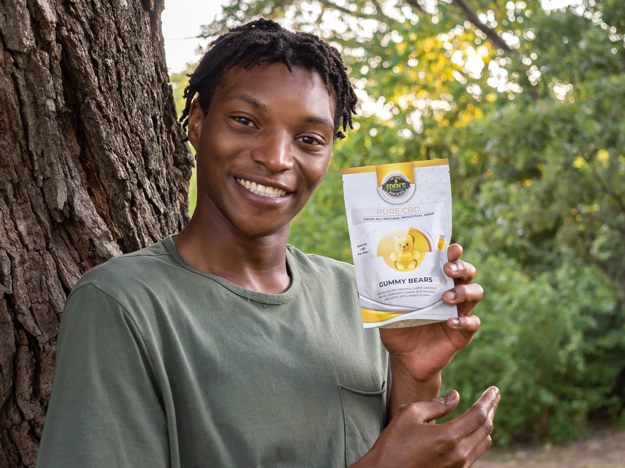 Smiling man in nature holding up a bag of CBD gummies