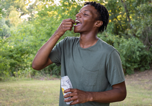 Young man in a park eating a cbd gummy from edens herbals