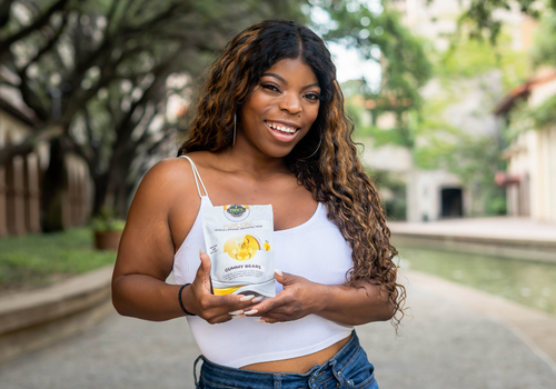 Woman smiling and holding up bag of cbd gummies from edens herbals