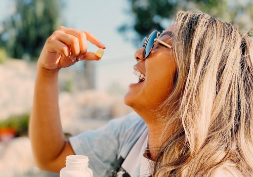 Woman in sunny outdoors placing cbd gummy in her mouth