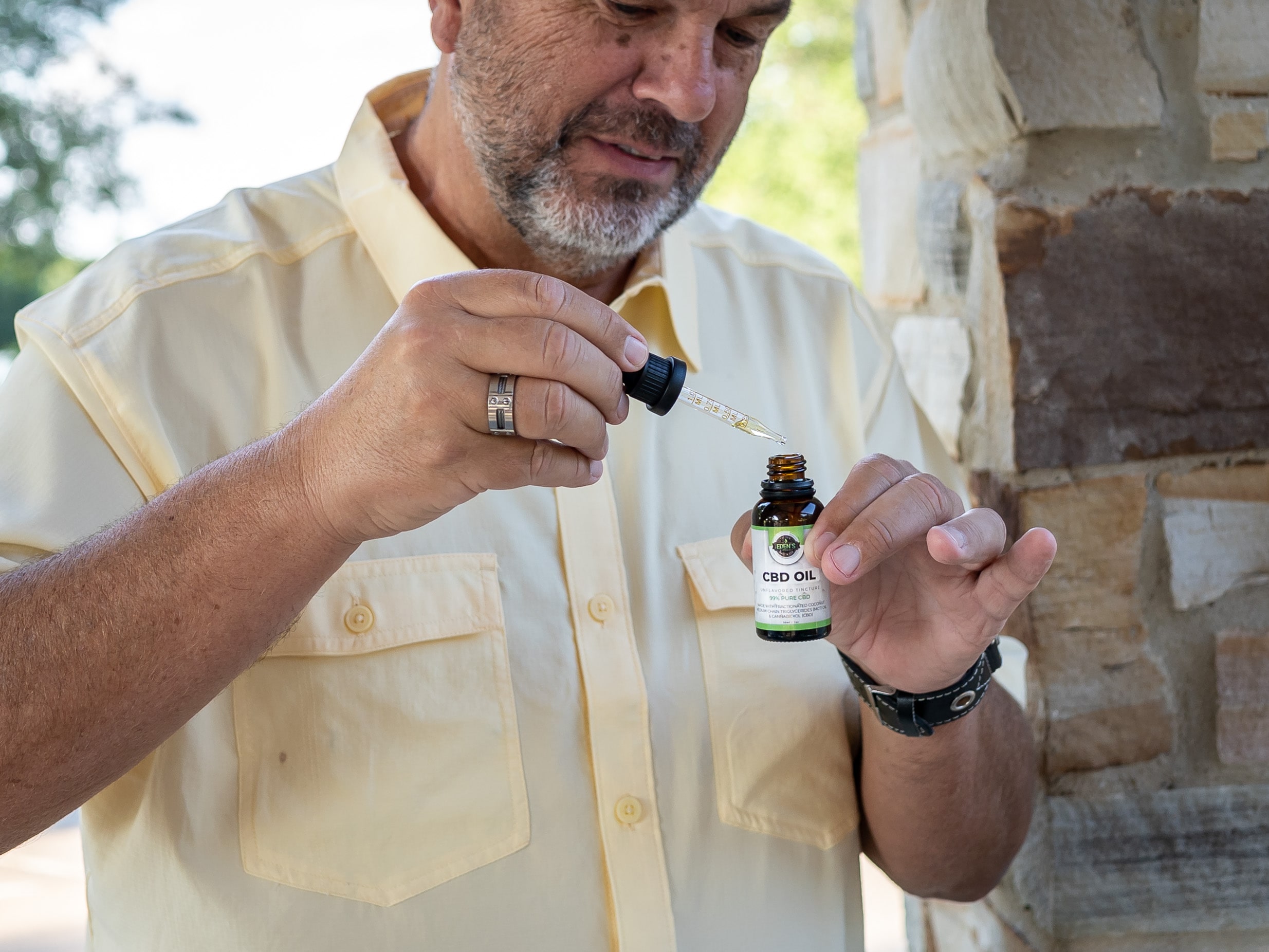 Older man holding and looking at CBD oil tincture
