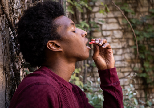 Closeup profile shot of young man placing a cbd gummy in his mouth