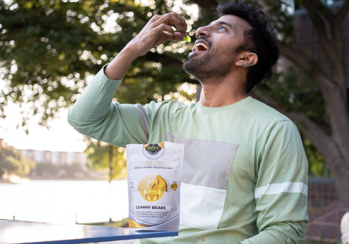 Man sitting at a table outdoors eating a cbd gummy bear from edens herbals