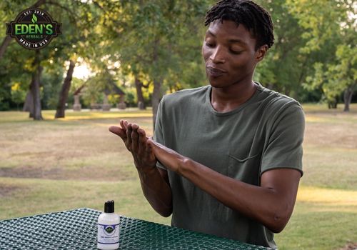 man applying eden's herbals cbd lotion to hands in a park