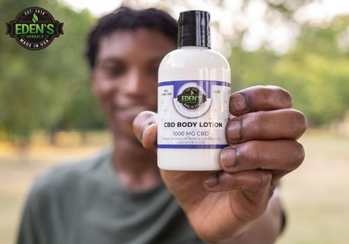 man holding eden's herbals cbd lotion up to camera with smile on his face