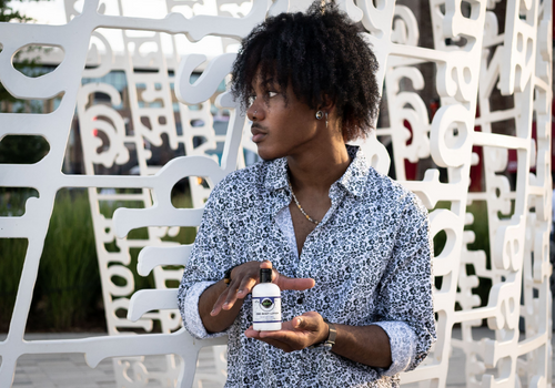 Young man holding a bottle of cbd lotion from edens herbals