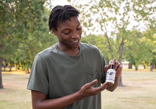 Man holding and examining a bottle of cbd lotion from edens herbals