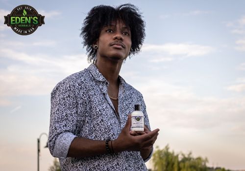 man holding eden's herbals cbd lotion in a sunset