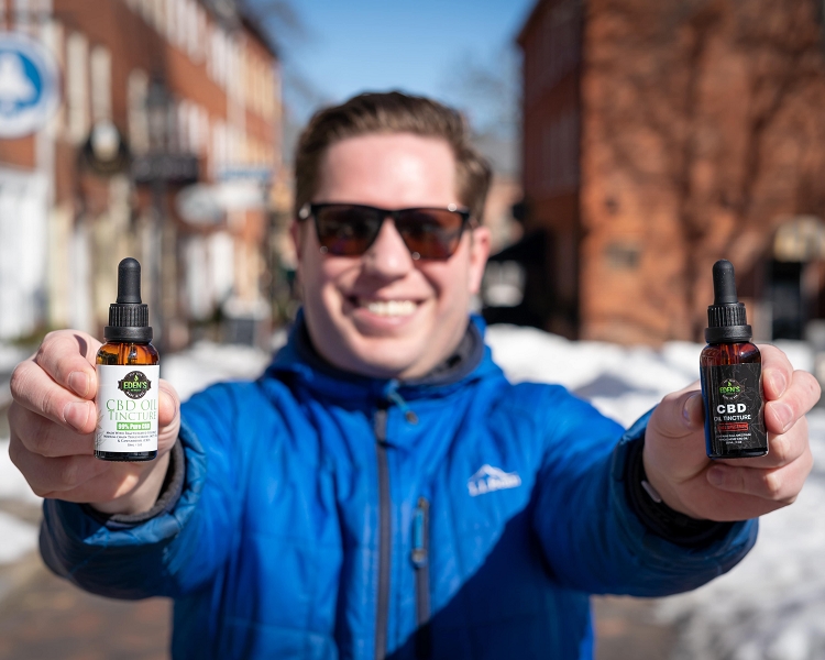 Man holding up two different types of flavored CBD oil tinctures