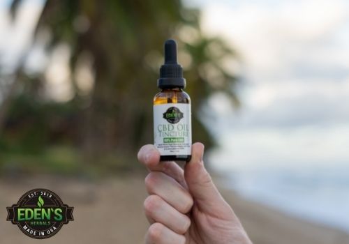 Eden's Herbals CBD oil being held on a beach