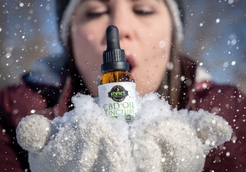 Woman blowing snow around a tincture of THC-free CBD oil