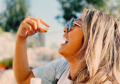 Closeup of young woman putting CBD capsule into her mouth