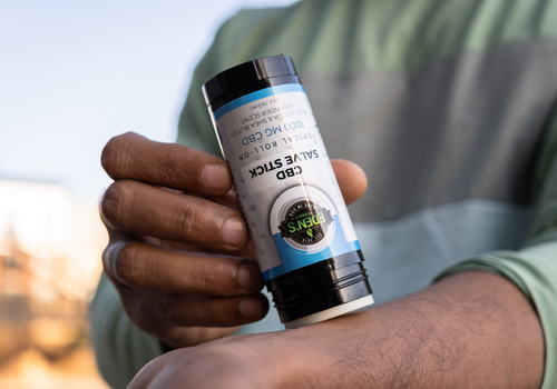 Closeup of man applying a cbd salve stick to his forearm