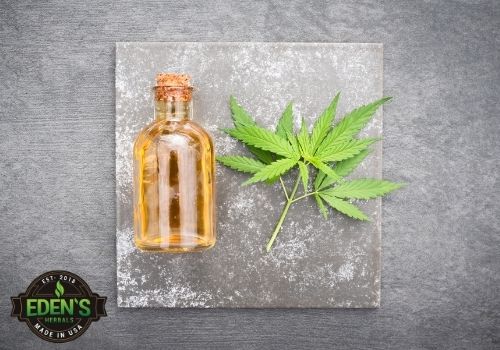 CBD hemp leaf and cbd oil bottle laid out on a table