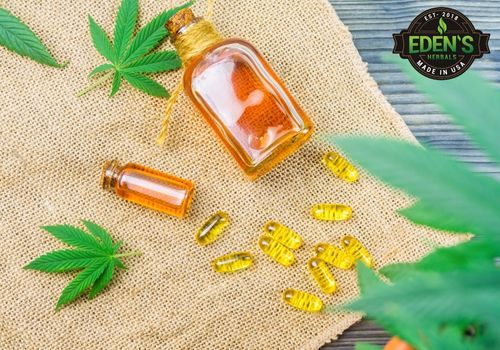 cbd oil and capsules on a table around hemp leaves