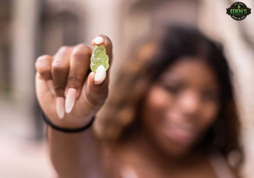 woman holding eden's herbals cbd gummy close to camera