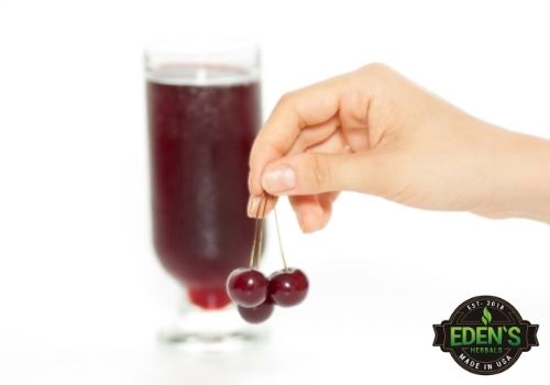 cup of cherry juice with woman holding fresh cherries