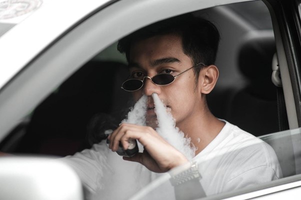 Man smoking his e-cigarette in a car