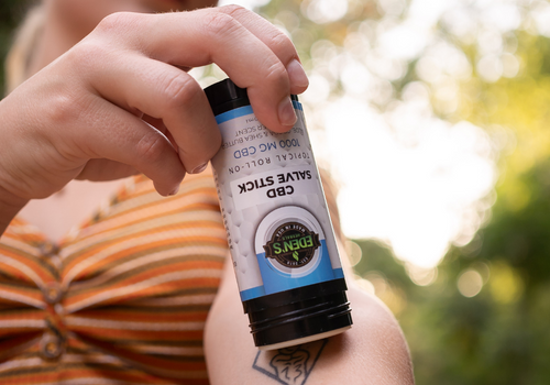 Closeup of woman applying CBD salve stick to her arm