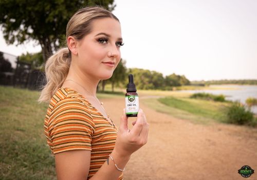 woman smiling in park holding eden's herbals full spectrum cbd oil