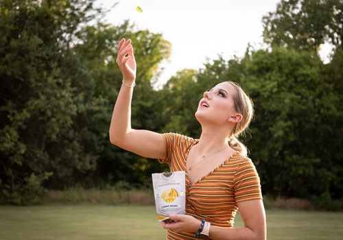 Young woman in a park tossing cbd gummy bear up into the air to catch in her mouth