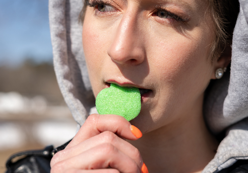 Closeup of woman with sour apple cbd gummy in her mouth