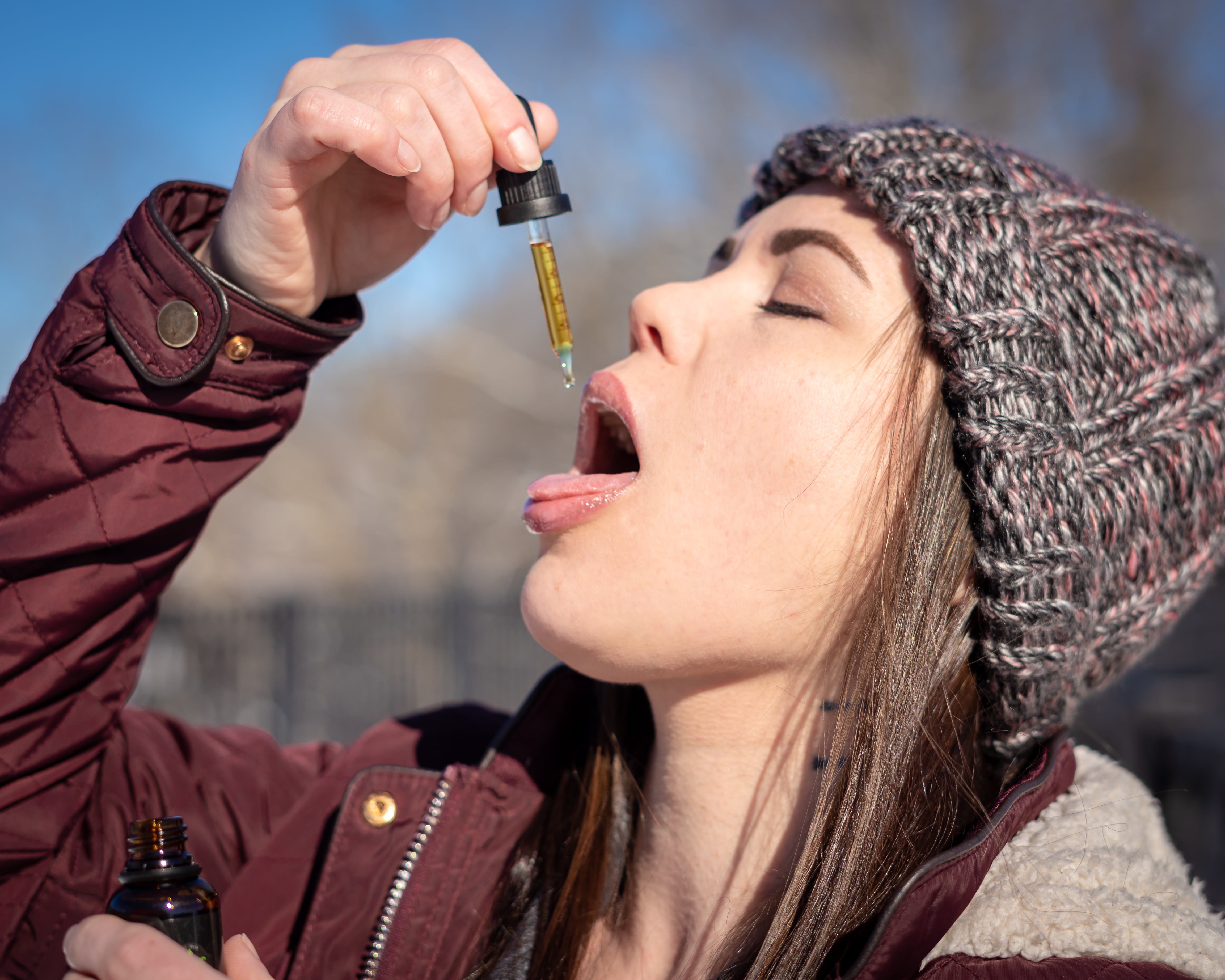 Woman taking CBD oil from tincture placed in mouth