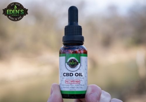 Hand holding full spectrum cbd oil tincture with full dropper