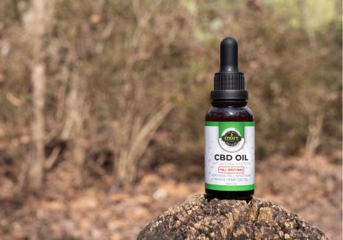 Tincture of full spectrum cbd oil sitting on a stump in forest