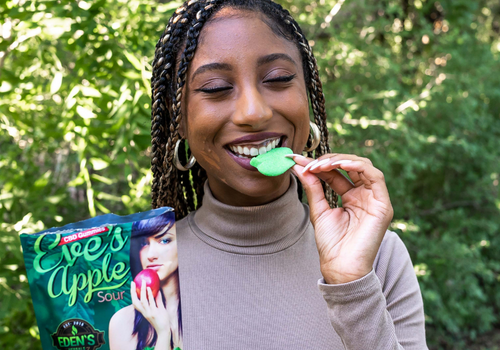 Closeup of woman eating a large sour apple CBD gummy outdoors