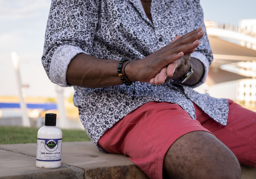 Young man sitting on a bench rubbing cbd lotion into his hands