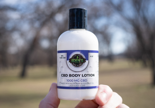 Closeup of hand holding a bottle of cbd lotion from edens herbals