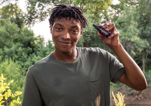 Young man holding up a tincture of full-spectrum CBD oil from eden's herbals