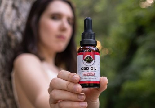 Woman holding up a tincture of cinnamon flavored full spectrum cbd oil