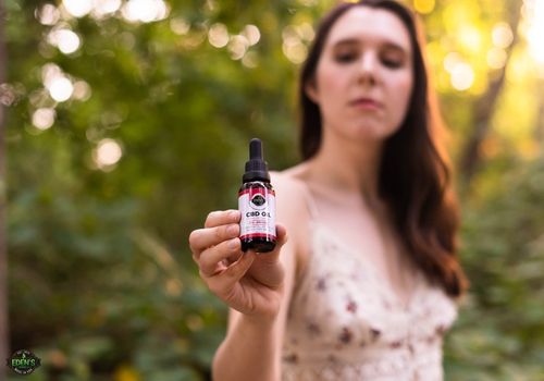 woman in flower dress holding eden's herbals cbd oil in park